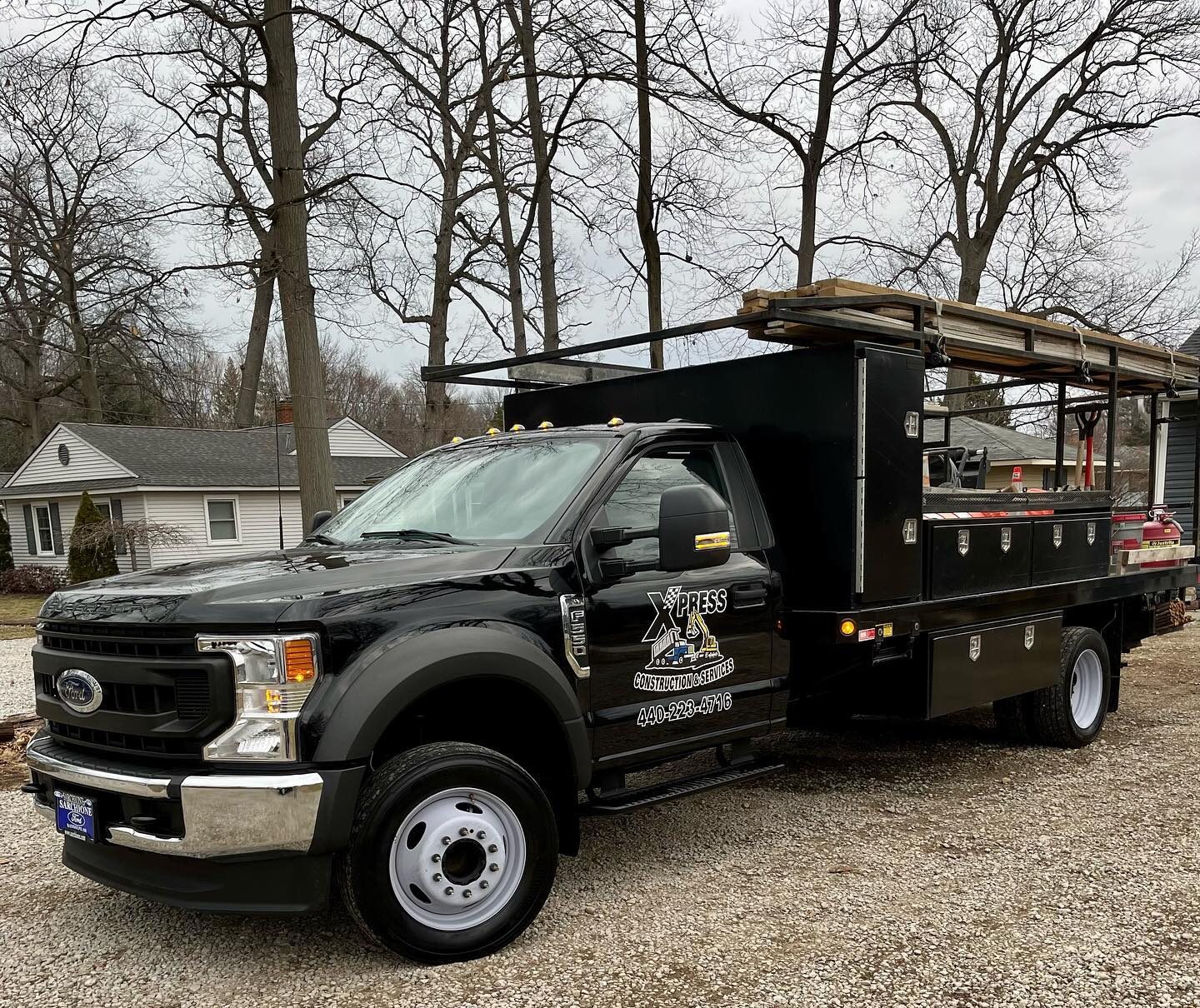 A Xpress Construction & Services truck is parked outside homes, showing company info for local construction work.