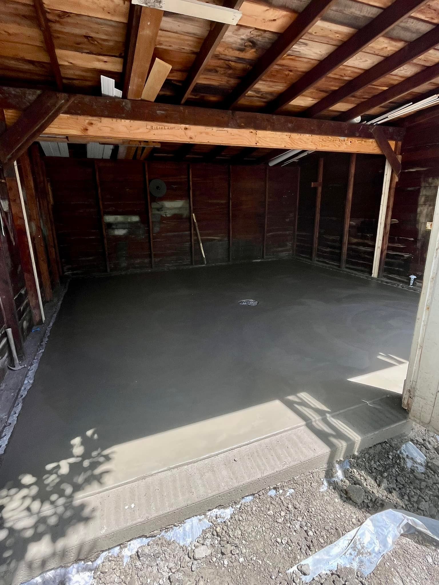 Xpress Construction & Services shows a new concrete floor in a garage, ready for use after recent construction work.
