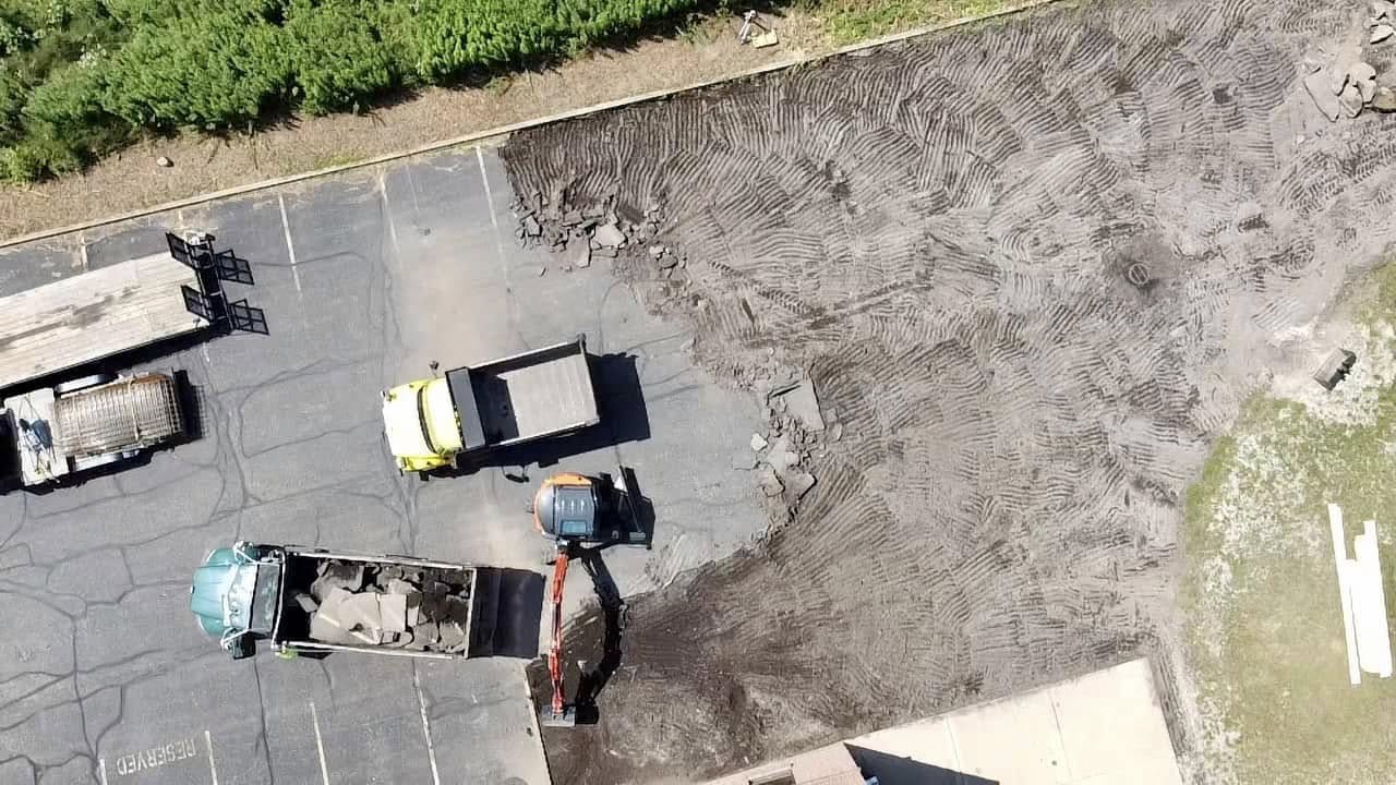 Xpress Construction & Services is building a new parking lot with heavy equipment and workers preparing the area for use.